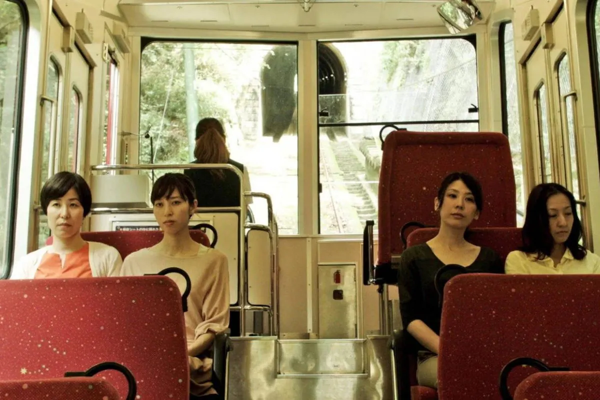 4 women sitting on a bus looking tired