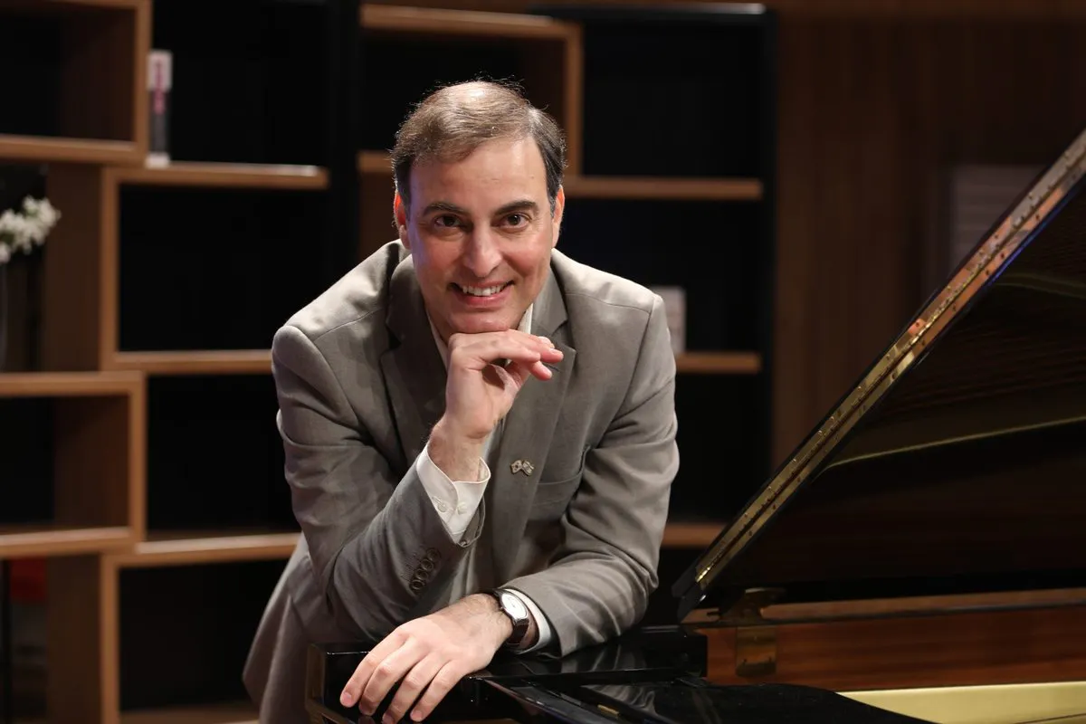 Portrait of Aviram Reichert posed near a piano