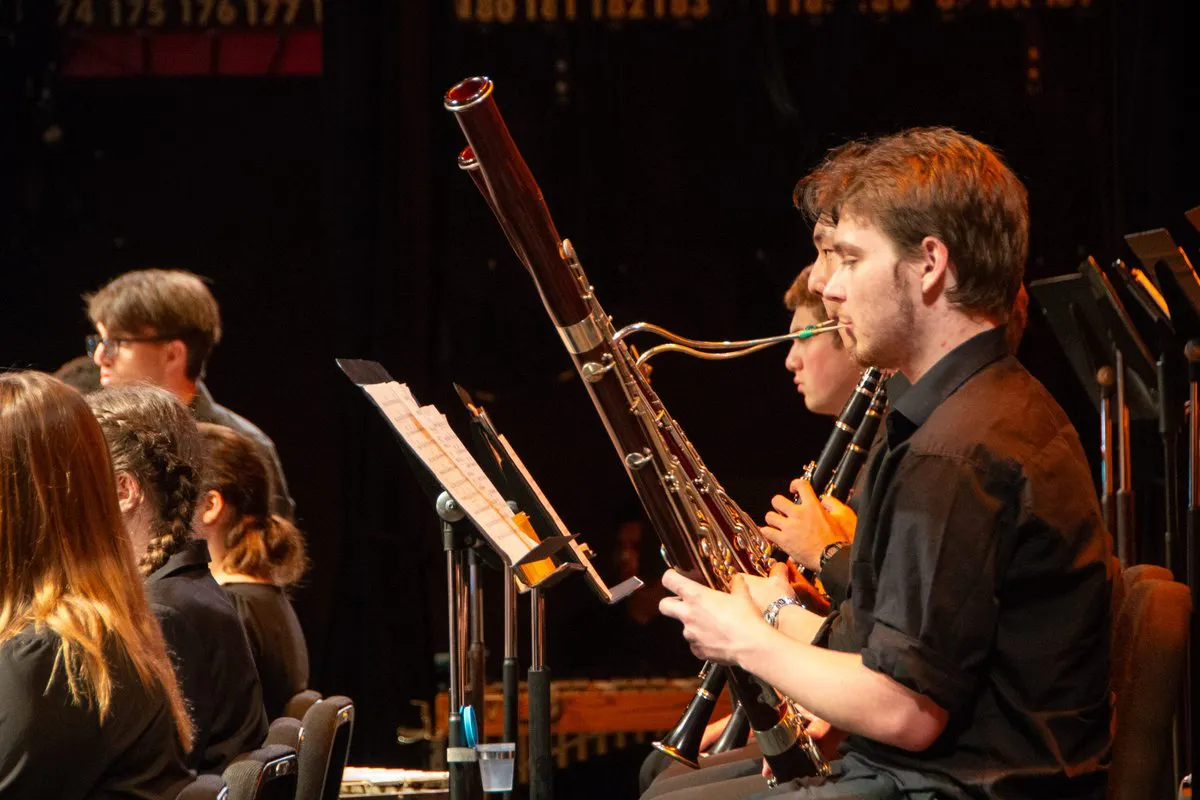 A bassoonist performs on stage with an orchestra