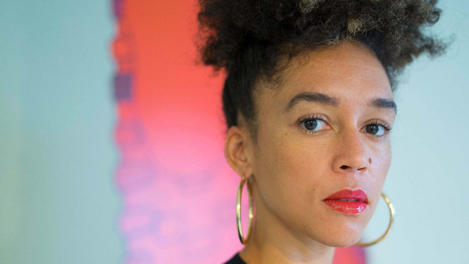 Headshot of Danielle Dean. She is wearing red lipstick and gold hoop earrings