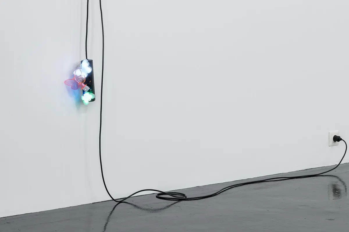 A black extension cord hangs from a wall, with three butterfly nightlights plugged into it