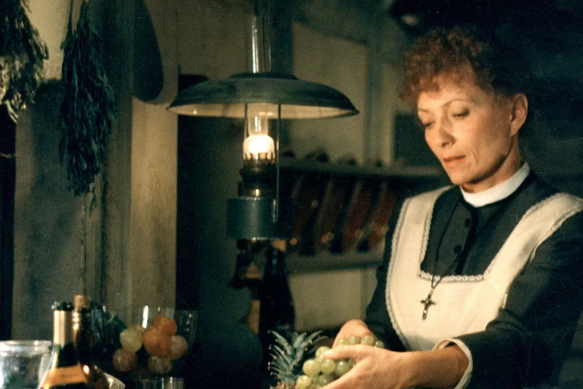 A woman in an apron handles a bunch of grapes