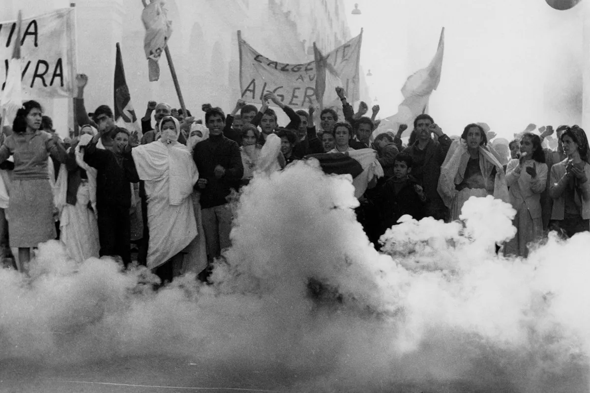 a bunch of people in protest holding signs. there is smoke around them
