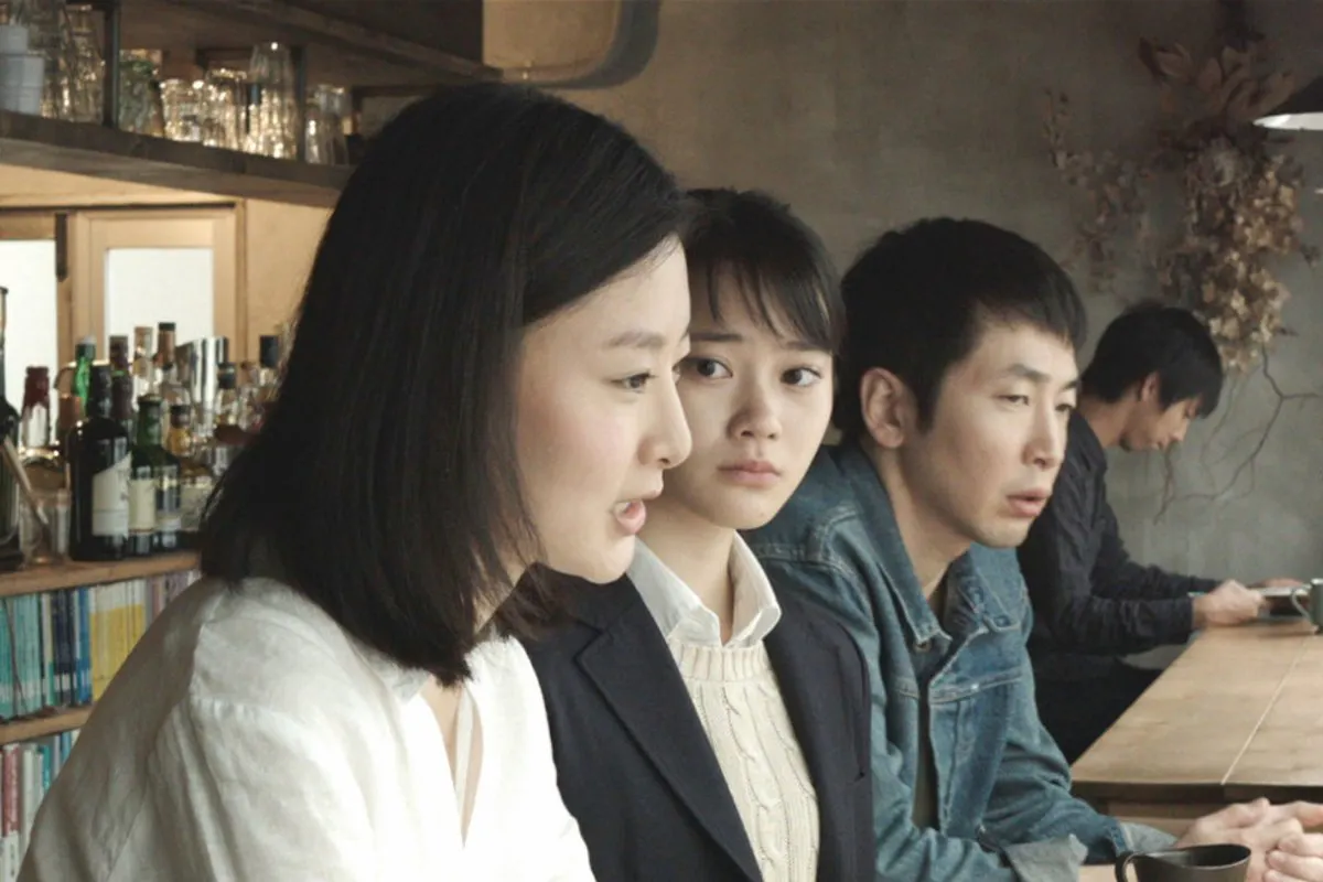 2 women and a man in a cafe looking out the window