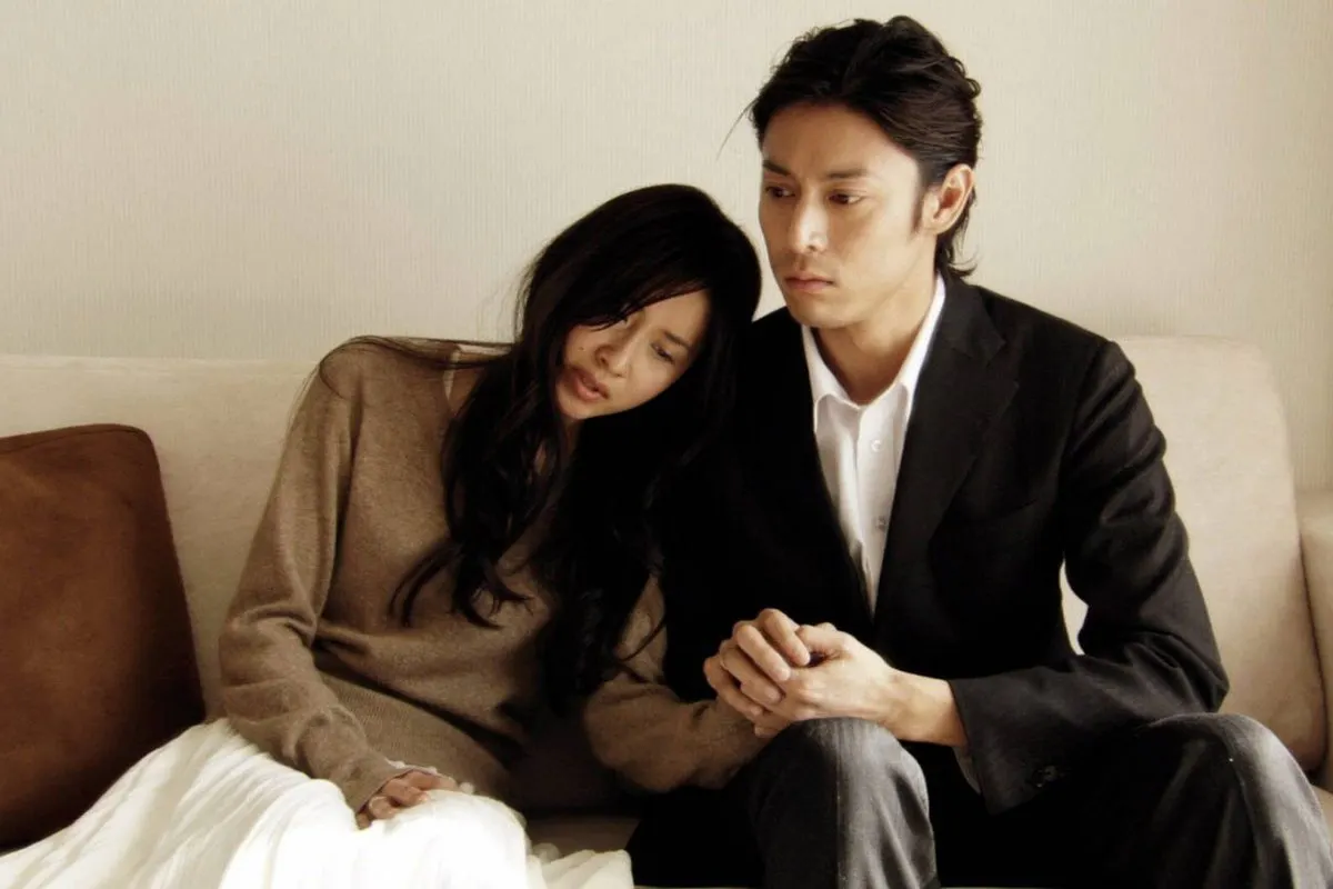 A man holding a woman's hand on a sofa.
