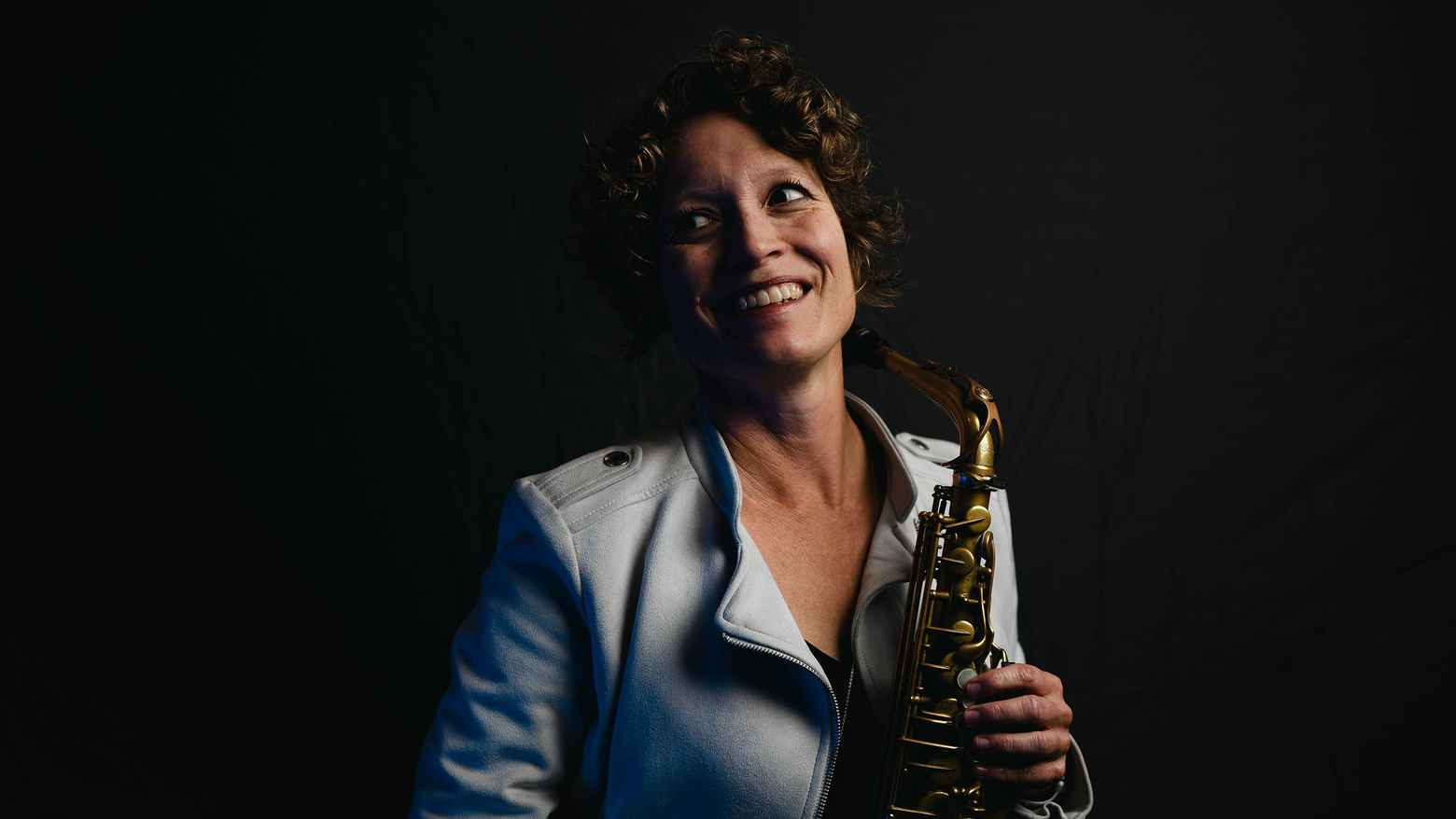 A saxophonist poses holding her instrument