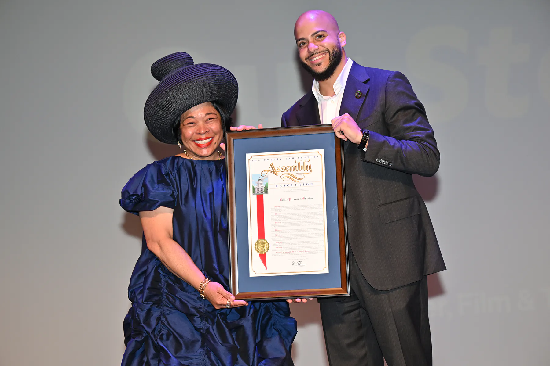 Dean celine and Isaac Bryan pose together holding a commendation from the California state assembly