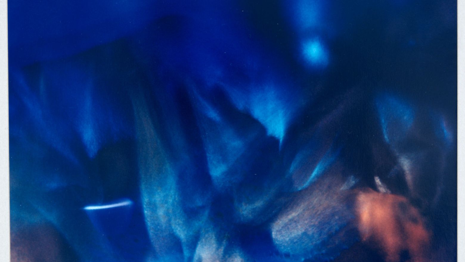 Detail view of a work by Wynn Bullock, titled Color Light Abstraction 1010, swooping shades of blue with a pop of refracted orange