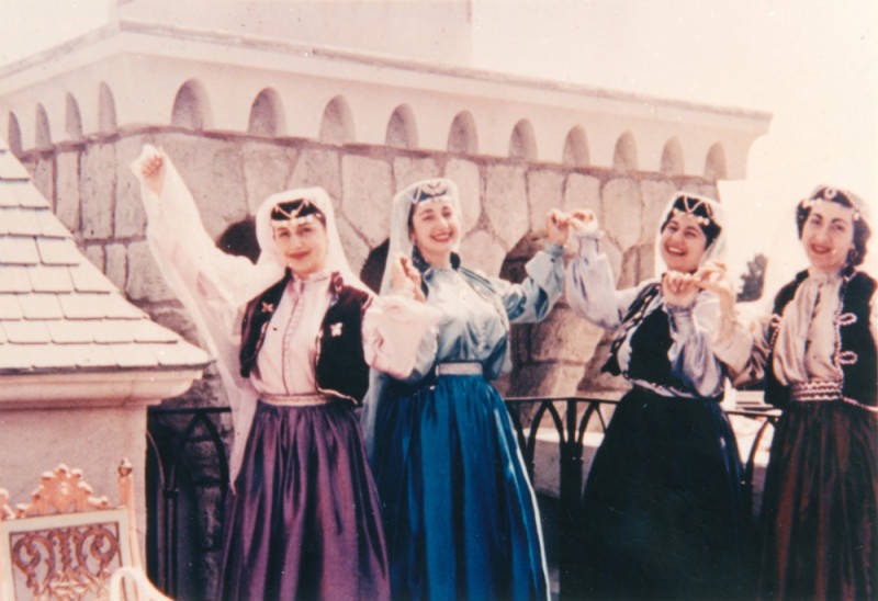 four women standing with arms raised while wearing traditional Armenian dress