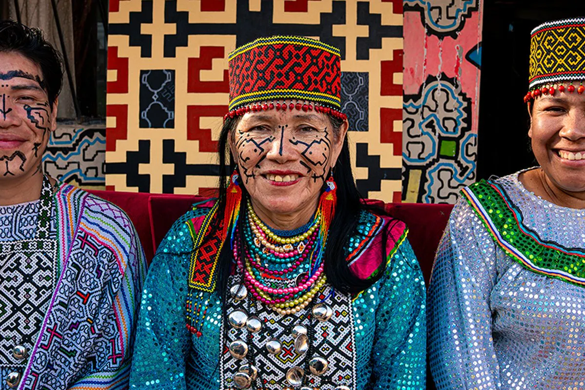 Three women in traditional regalia featuring intricate beaded head dress
