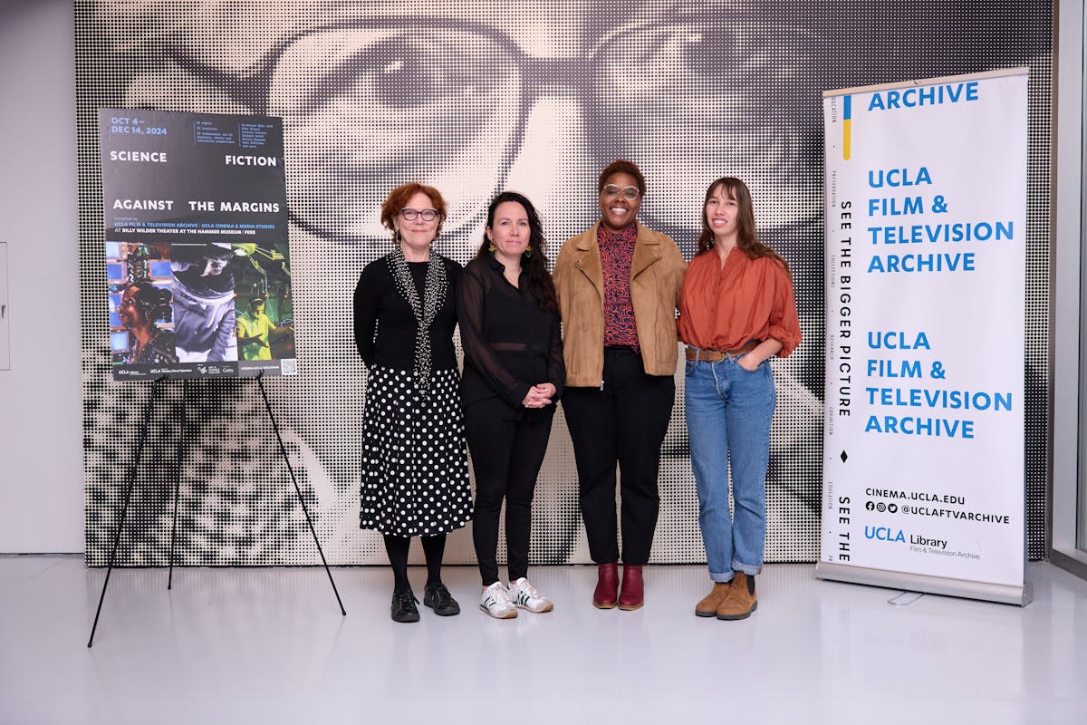 Four women stand in front of a poster at an event for the Science Fiction Against the Margins screening series at the Billy Wilder Theater at UCLA 