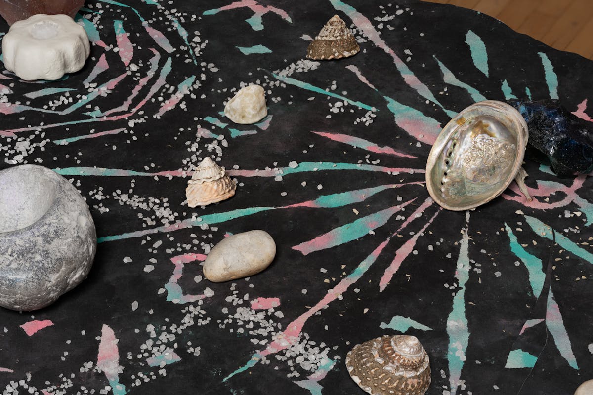 detail view of art by mercedes dorame using paint, stones and shells in a cosmic pattern