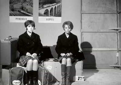 Two young women sitting on suitcases