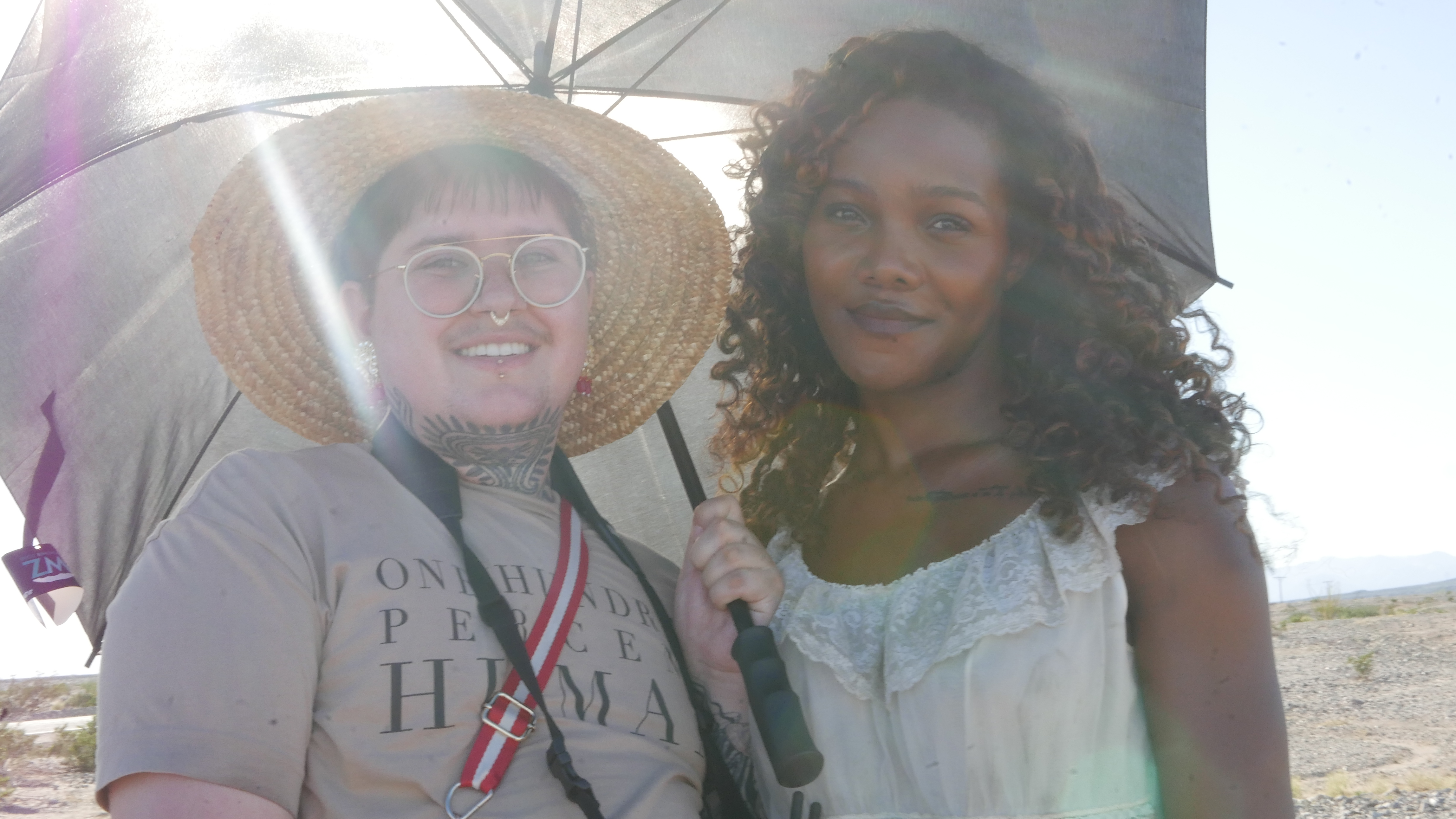 Filmmaker Kaith Karishma poses under an umbrella at a desert location with the star of their film 