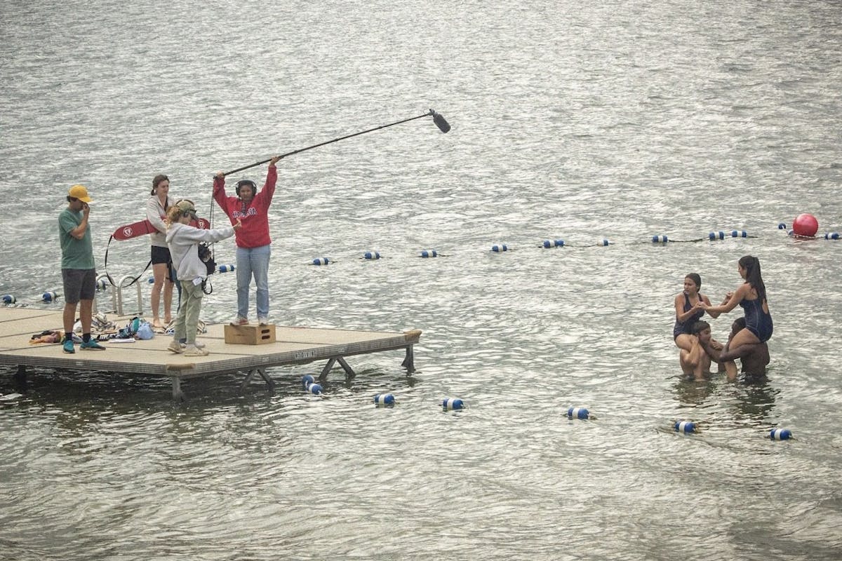 Standing on a floating dec, a film crew shoots a scene in the middle of a lake 