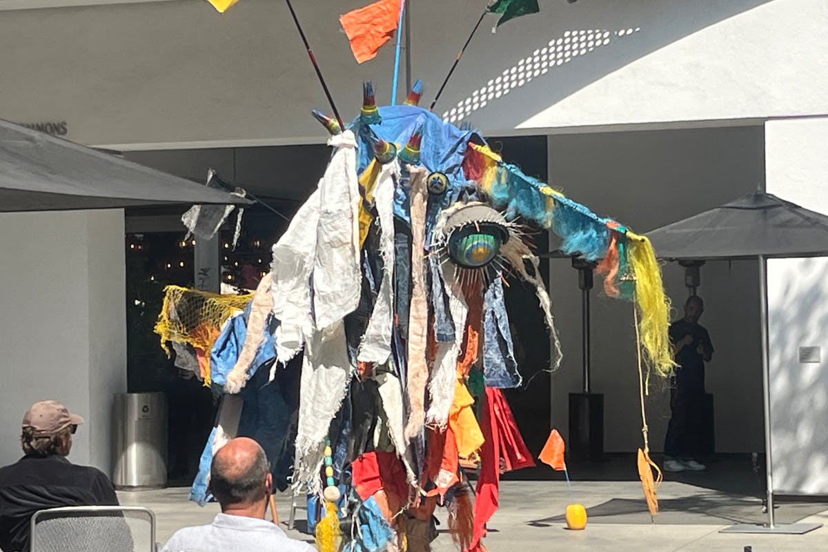 In the Hammer Museum courtyard, Artist Yangkura performs in a costume made from trash washed ashore in Korea 