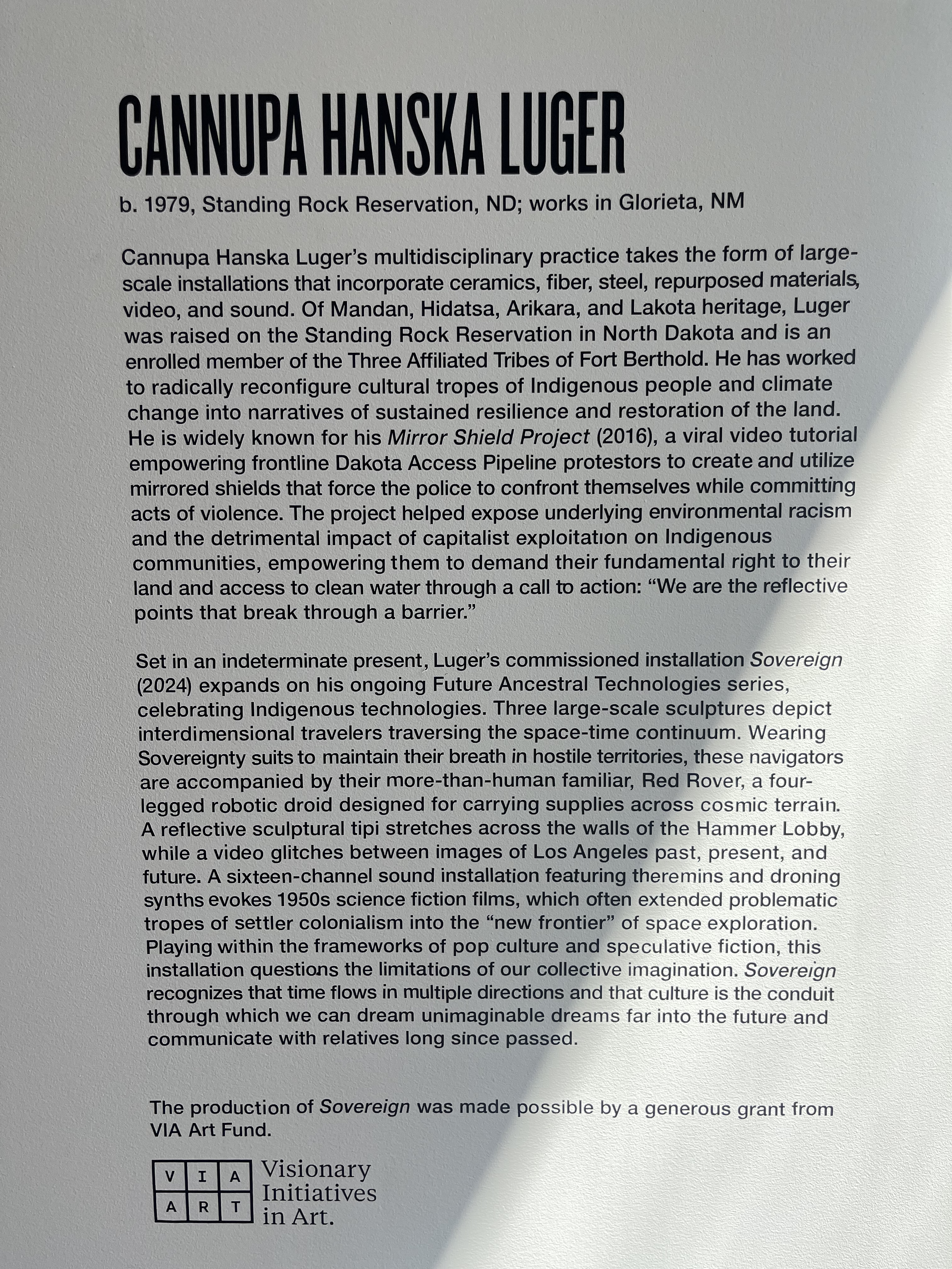 A photo of the gallery text that describes  Cannupa Hanska Luger's work on view in the Hammer Museum