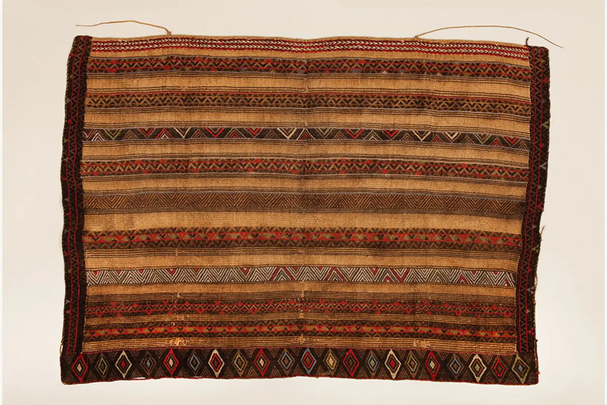 an intricate woven textile wall hanging in shades of brown and yellow and red