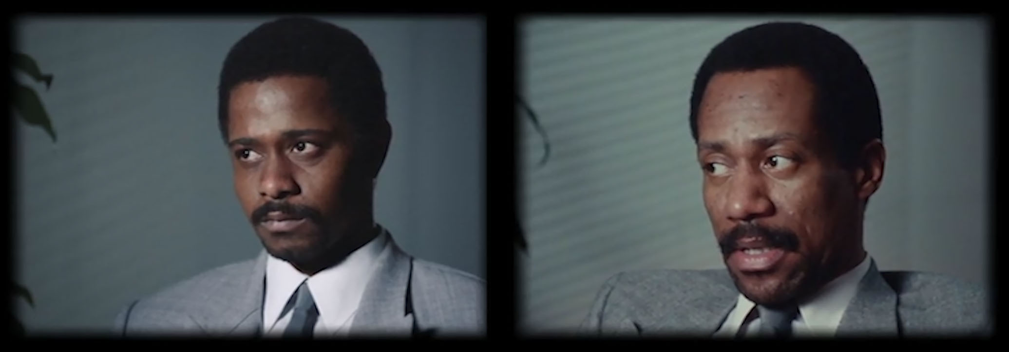 A man wearing a white button-down shirt, grey suit and tie