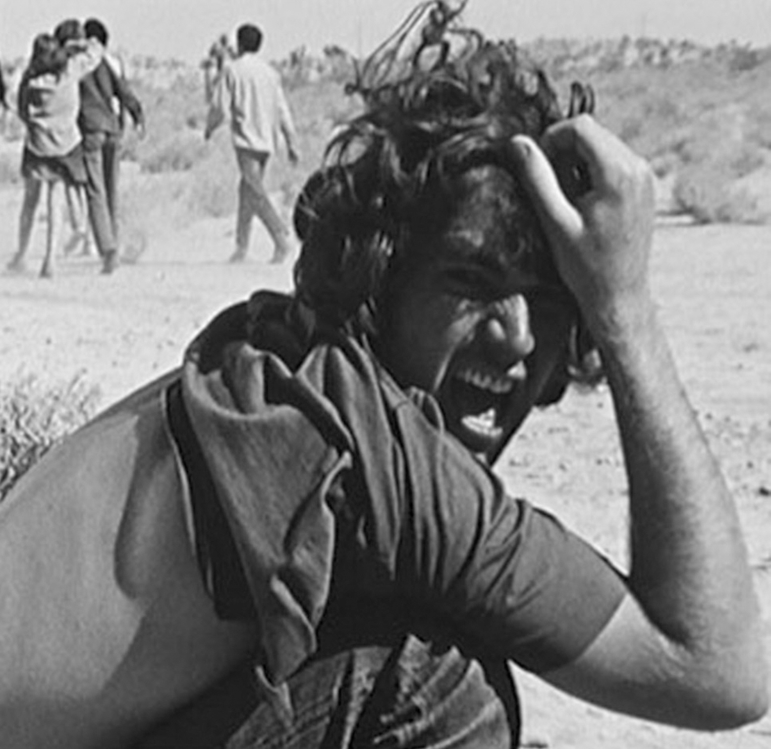 A black and white image of a person screaming while grabbing the top of their hair in their hand