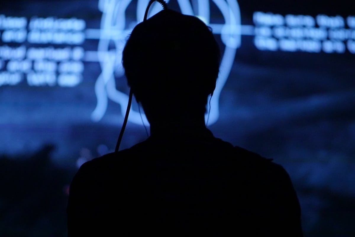 a person with a gaming helmet is seen in the shadow of a blue screen