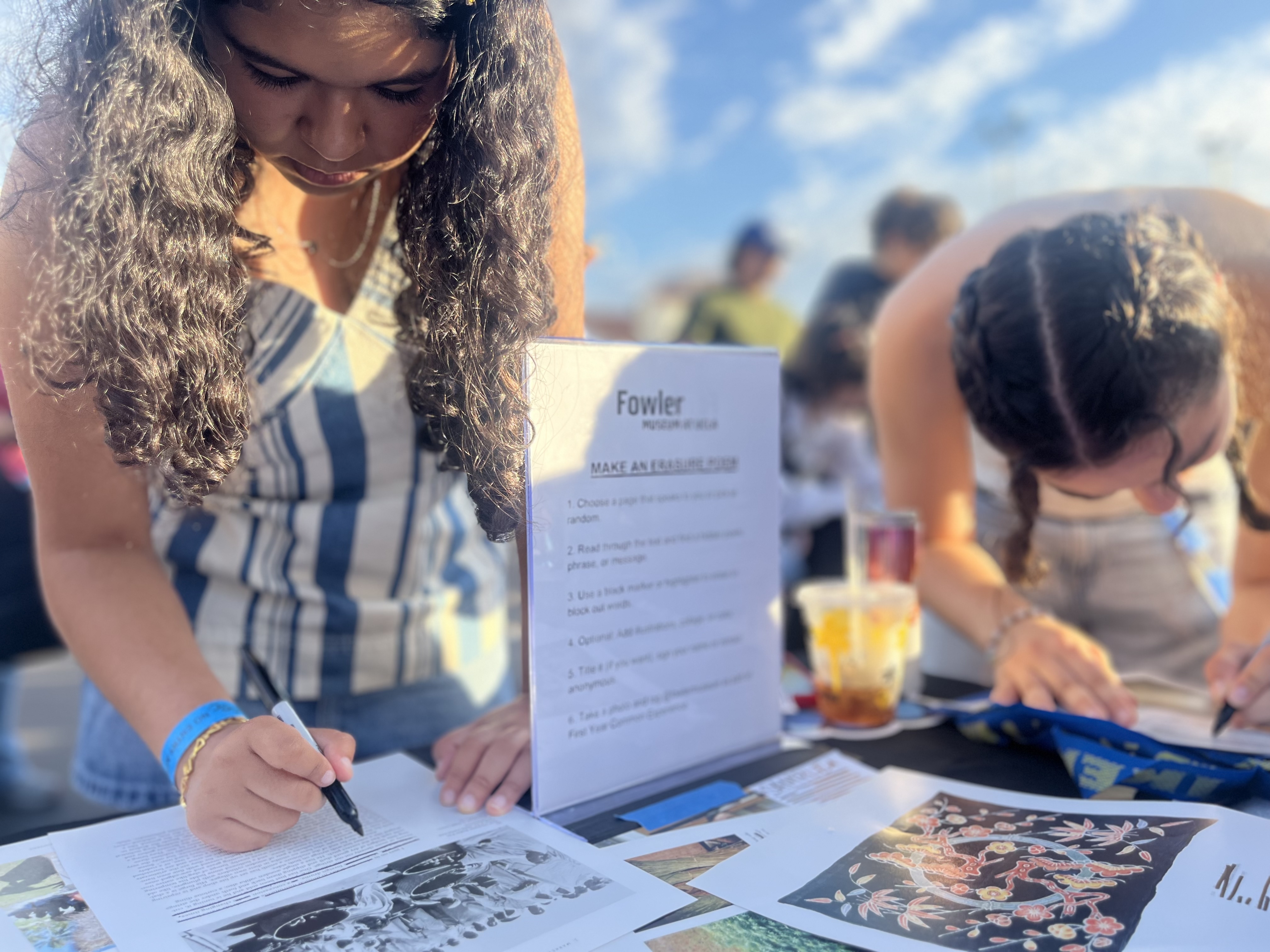several students use sharpies to black out words on a printed page to create an erasure poem
