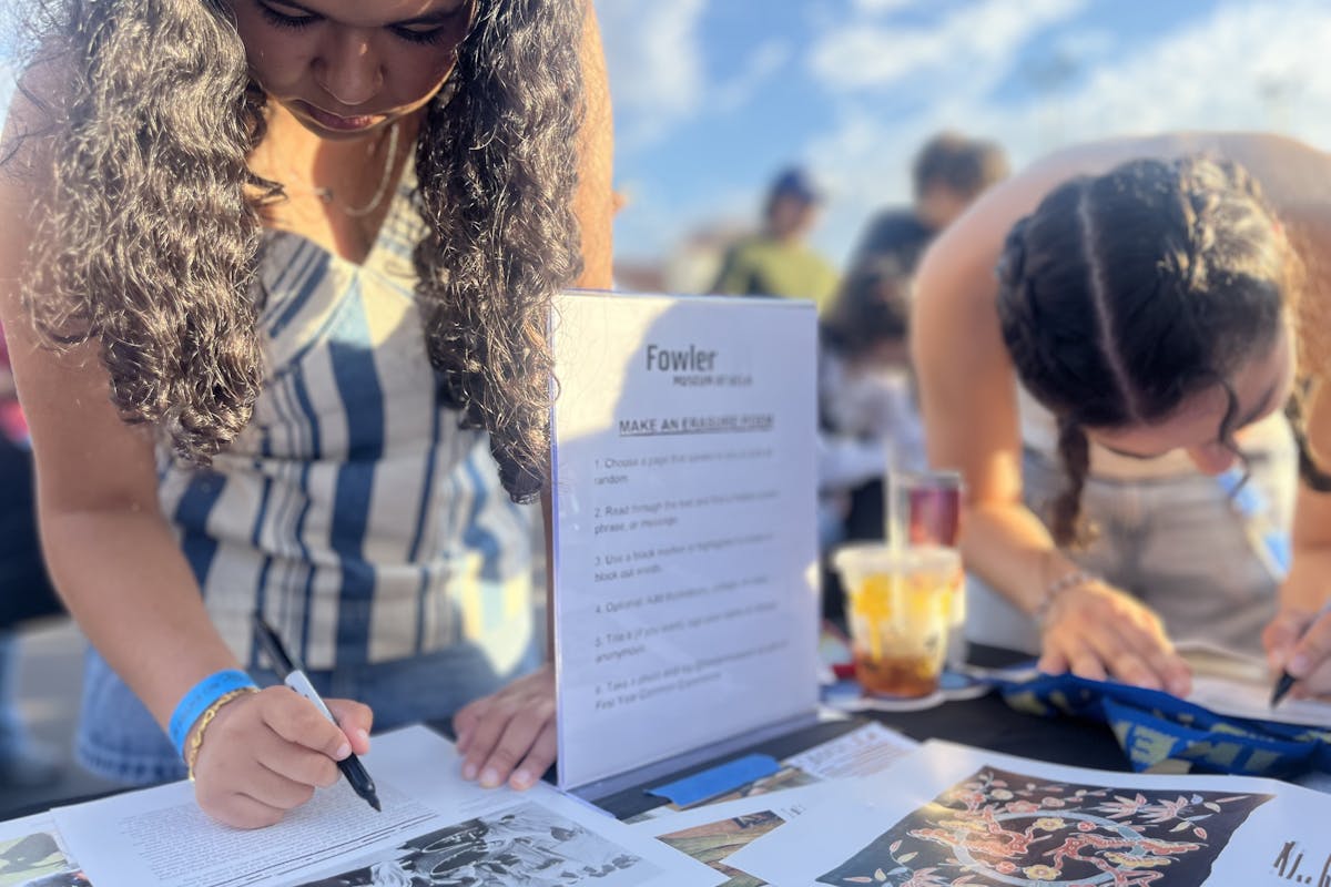 several students use sharpies to black out words on a printed page to create an erasure poem
