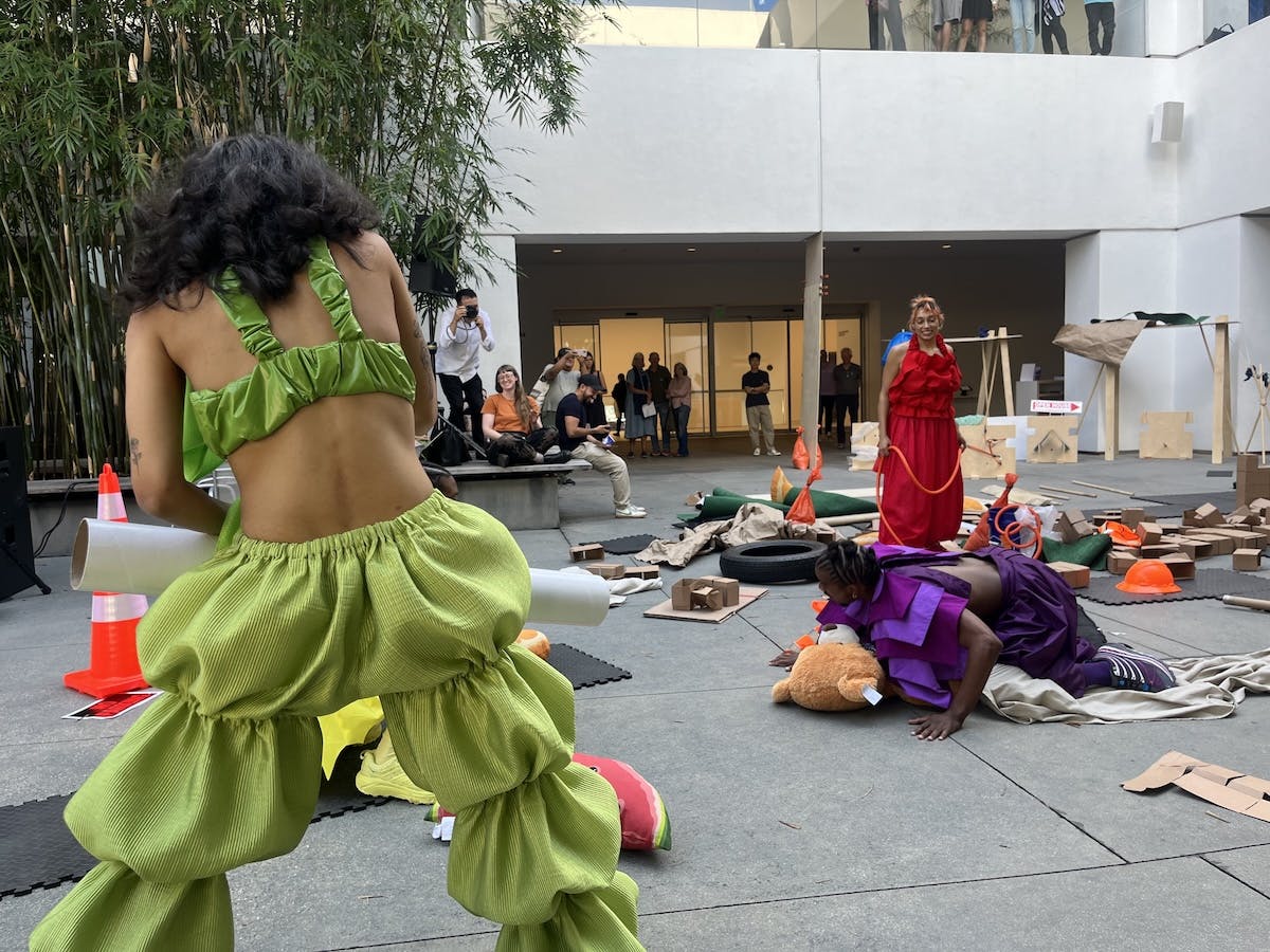 Performers in colorful costumes move through the Hammer Museum courtyard