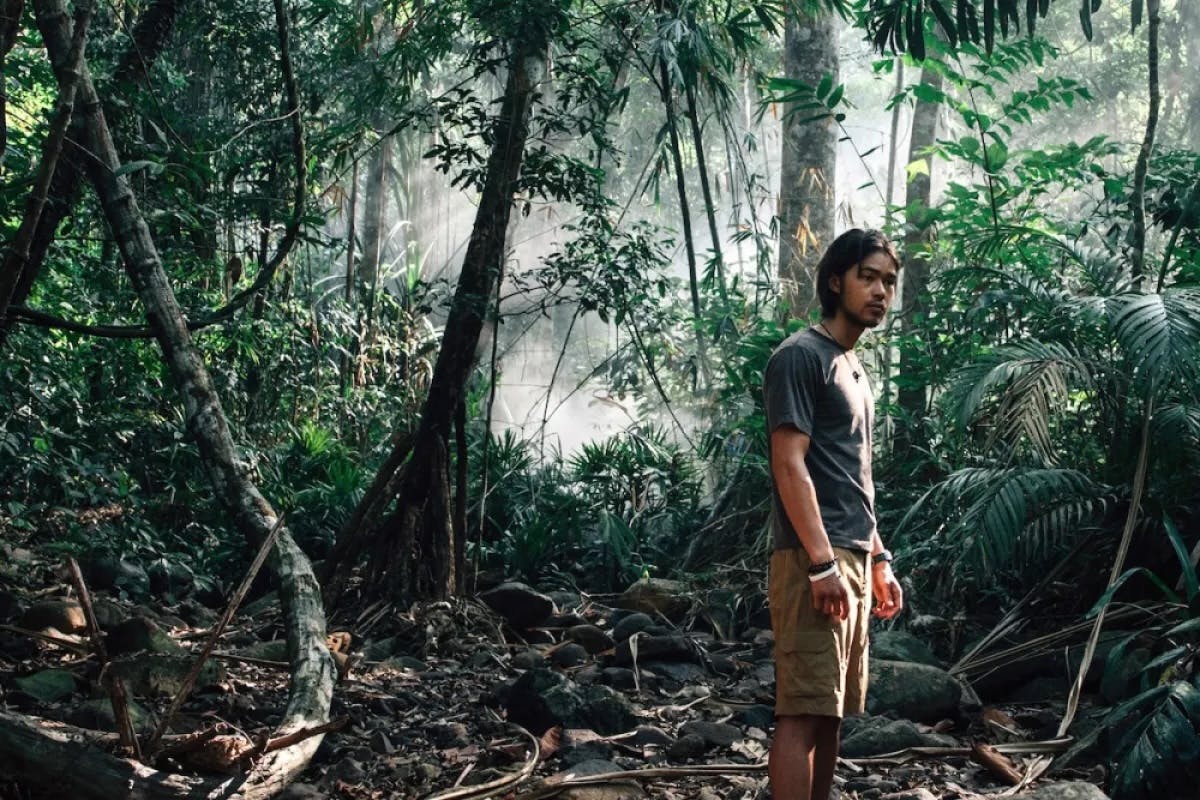 a young man stands alone in the middle of a lush jungle landscape. still from the film "Last Days"