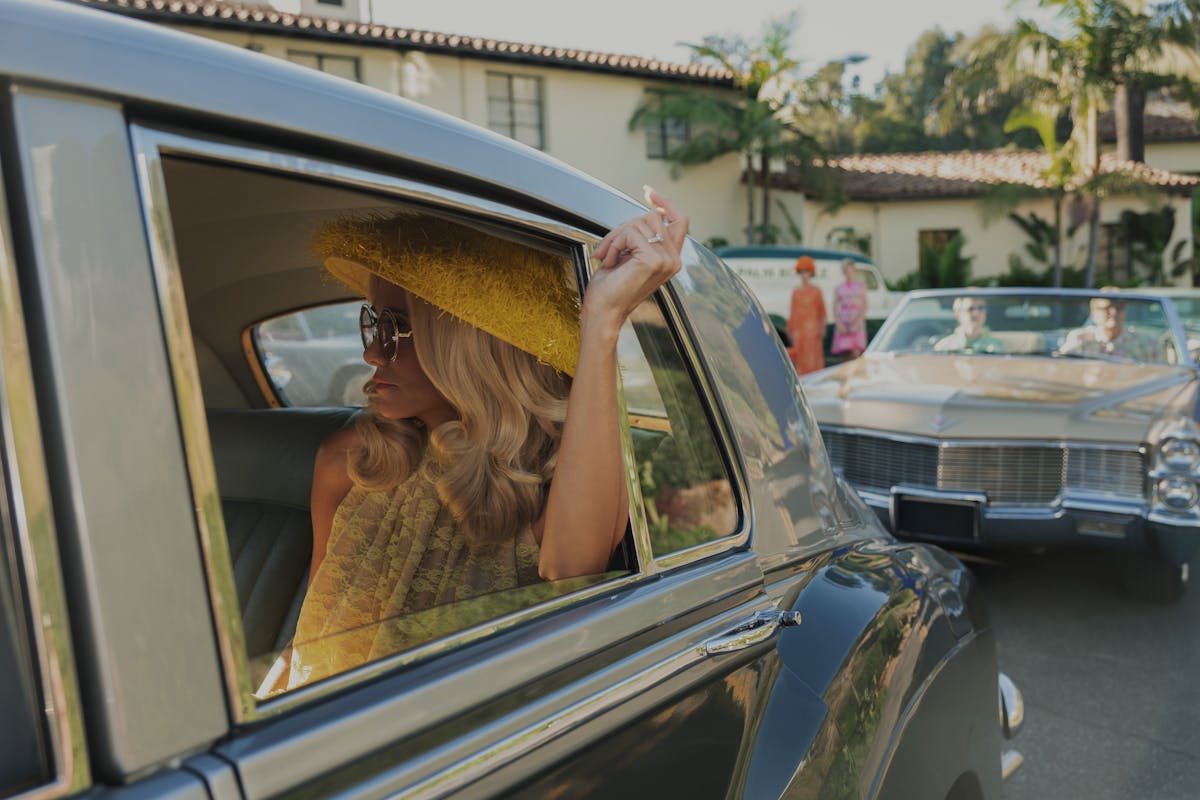 a woman in a yellow hat is in a vintage car