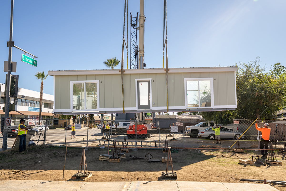 Part of a modular home is being lowered to the ground.