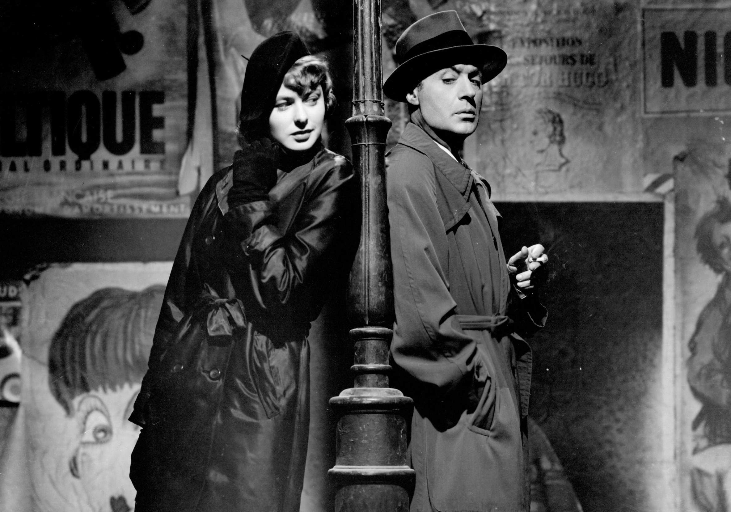 woman and man standing back to back against a streetlamp