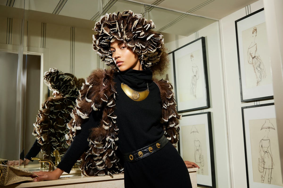 A model poses in a dramatic coat and hat designed by Bonnie Cashin