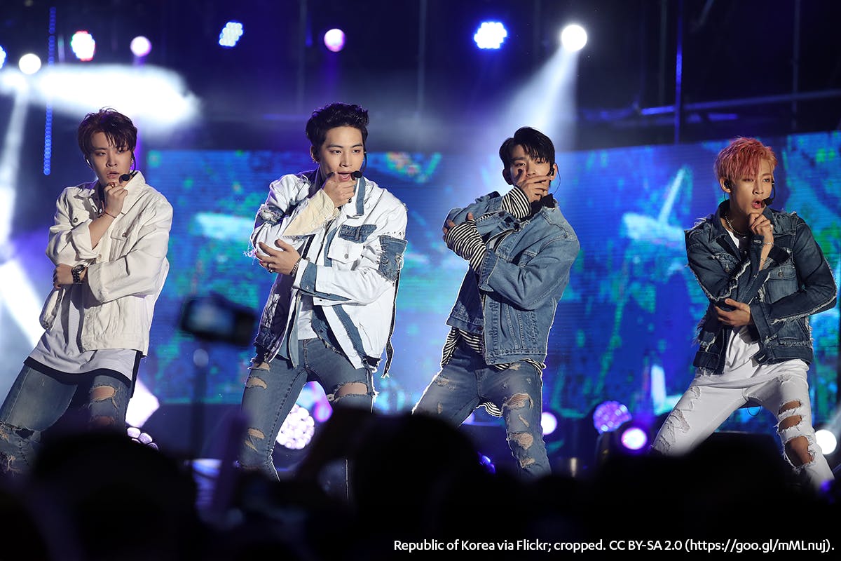 a group of four male kpop singers perform onstage