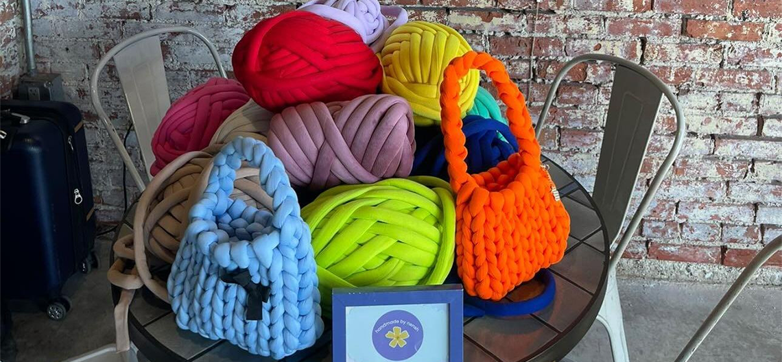 Brightly colored spools of yarn and several bags created with them