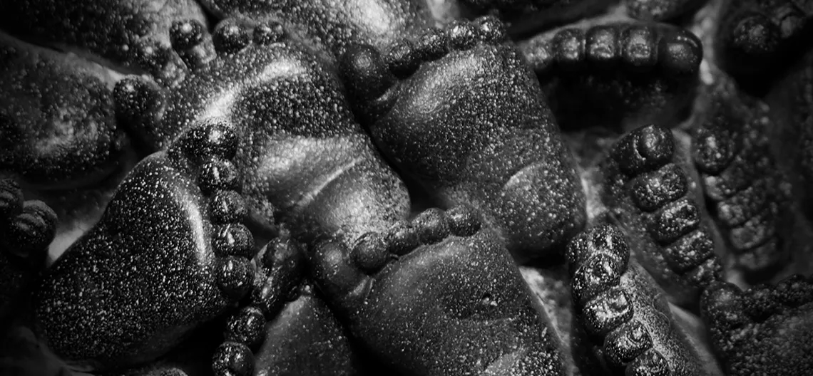 Closeup of a sculpture. Tiny feet carved into black stone