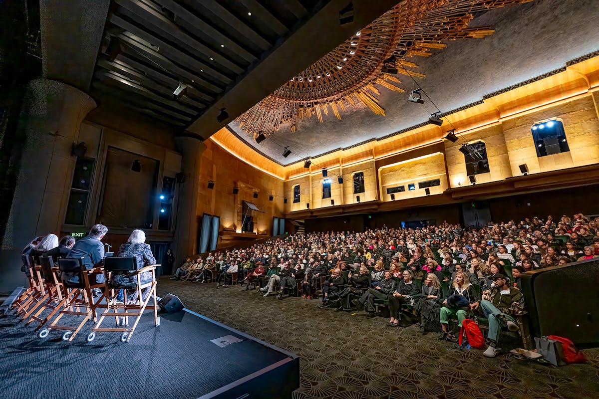 An audience listens to speakers on a stage