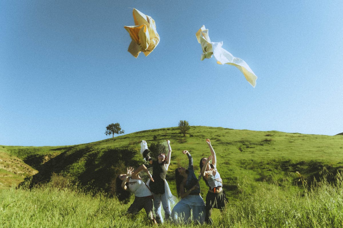 A small group of dancers in a green grassy field through bright yellow clothing into a blue sky