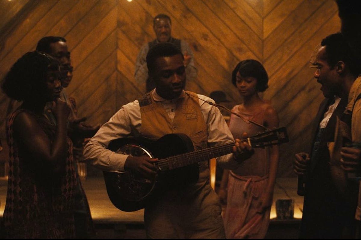 A man plays an acoustic guitar while several other people look on