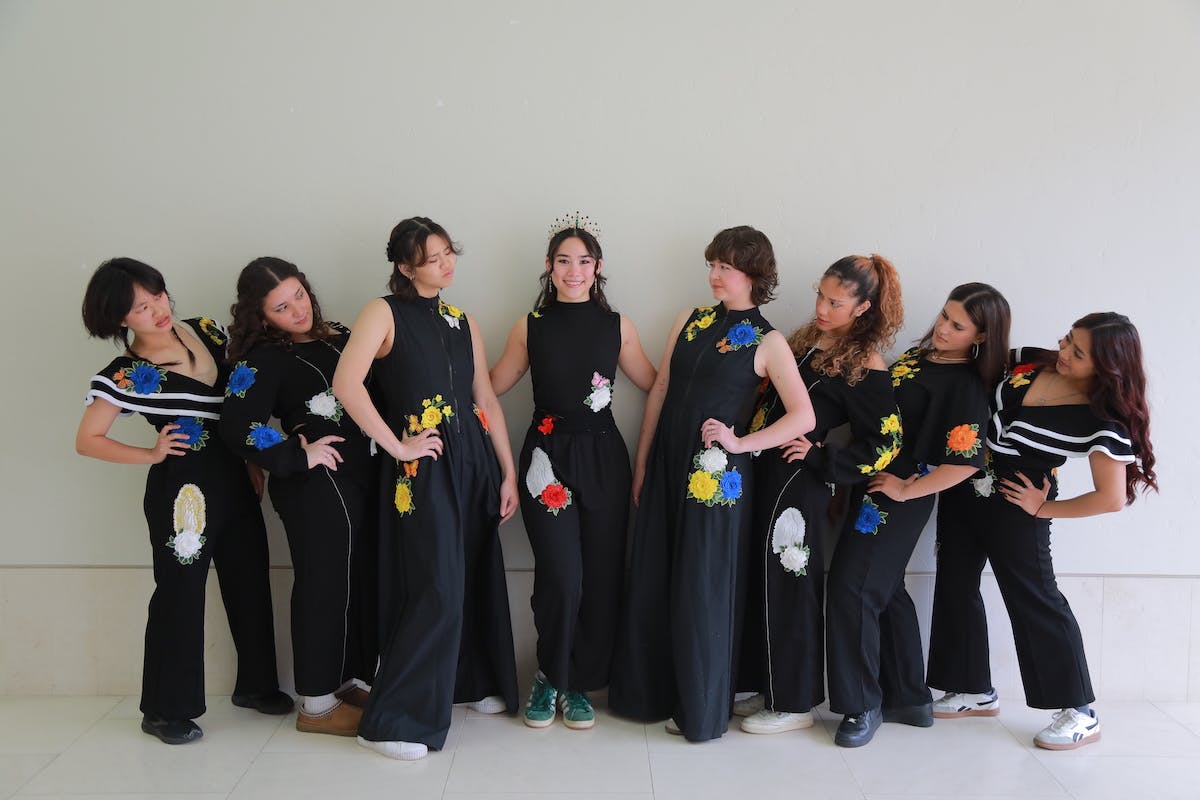 A group of dancers wearing black jumpsuits with colorful,  but minimalistic flower details.