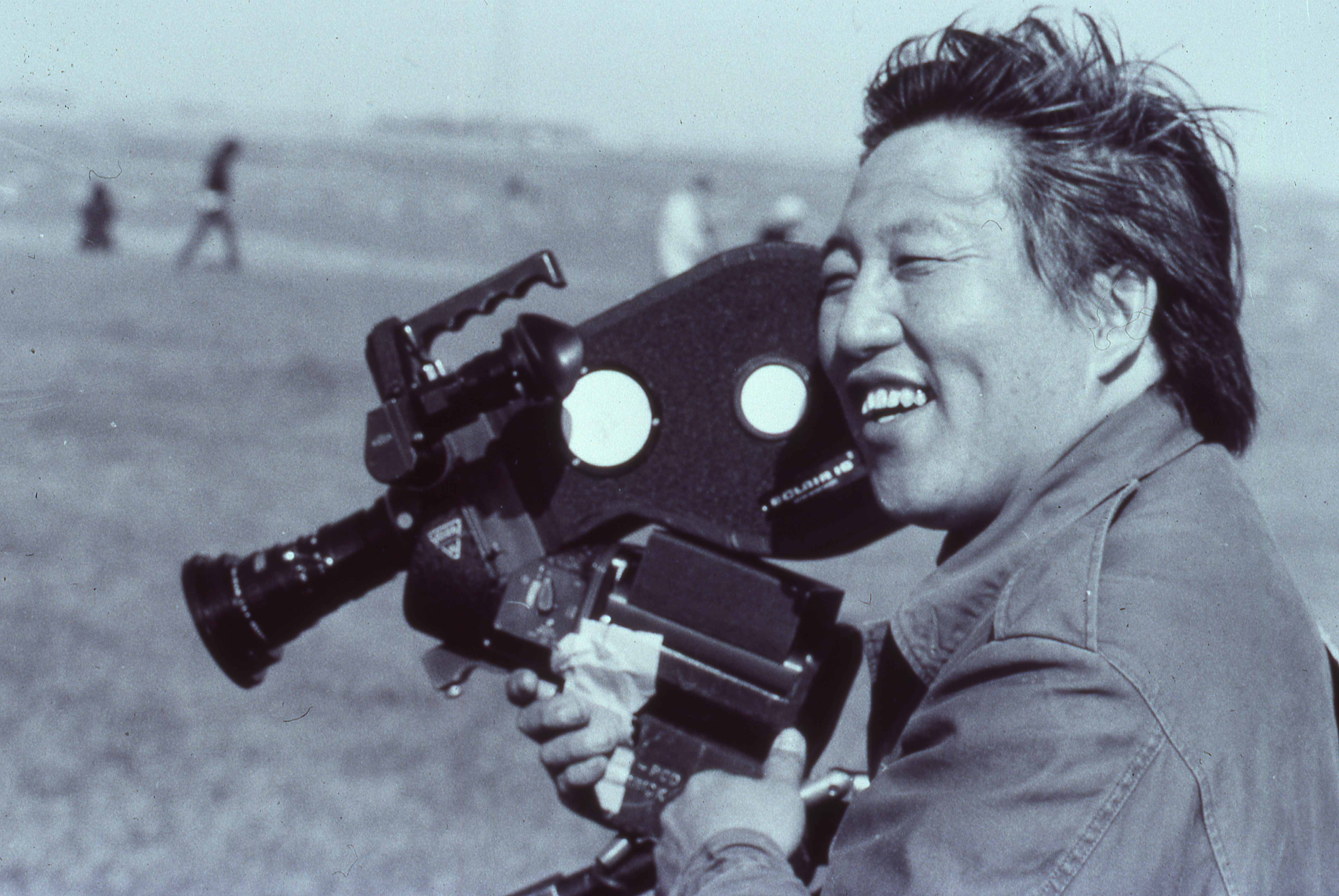 asian man smiling while holding a film camera up to his face
