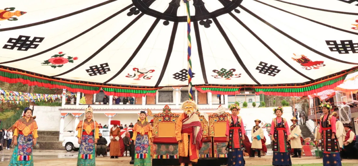 Dancers and singers in traditional garb perform under a white canopy