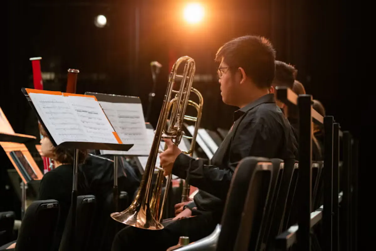 Side profile of a trombone player sitting on stage.