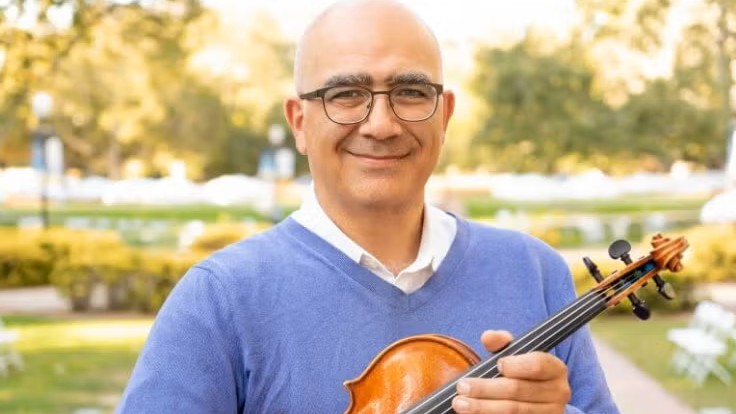 Portrait of Movses Pogossian. He is looking at the camera and holding his violin