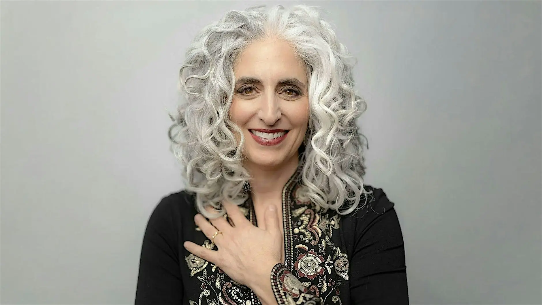 Cantor Elizabeth Shammash with her hand on her chest, smiling at the camera.