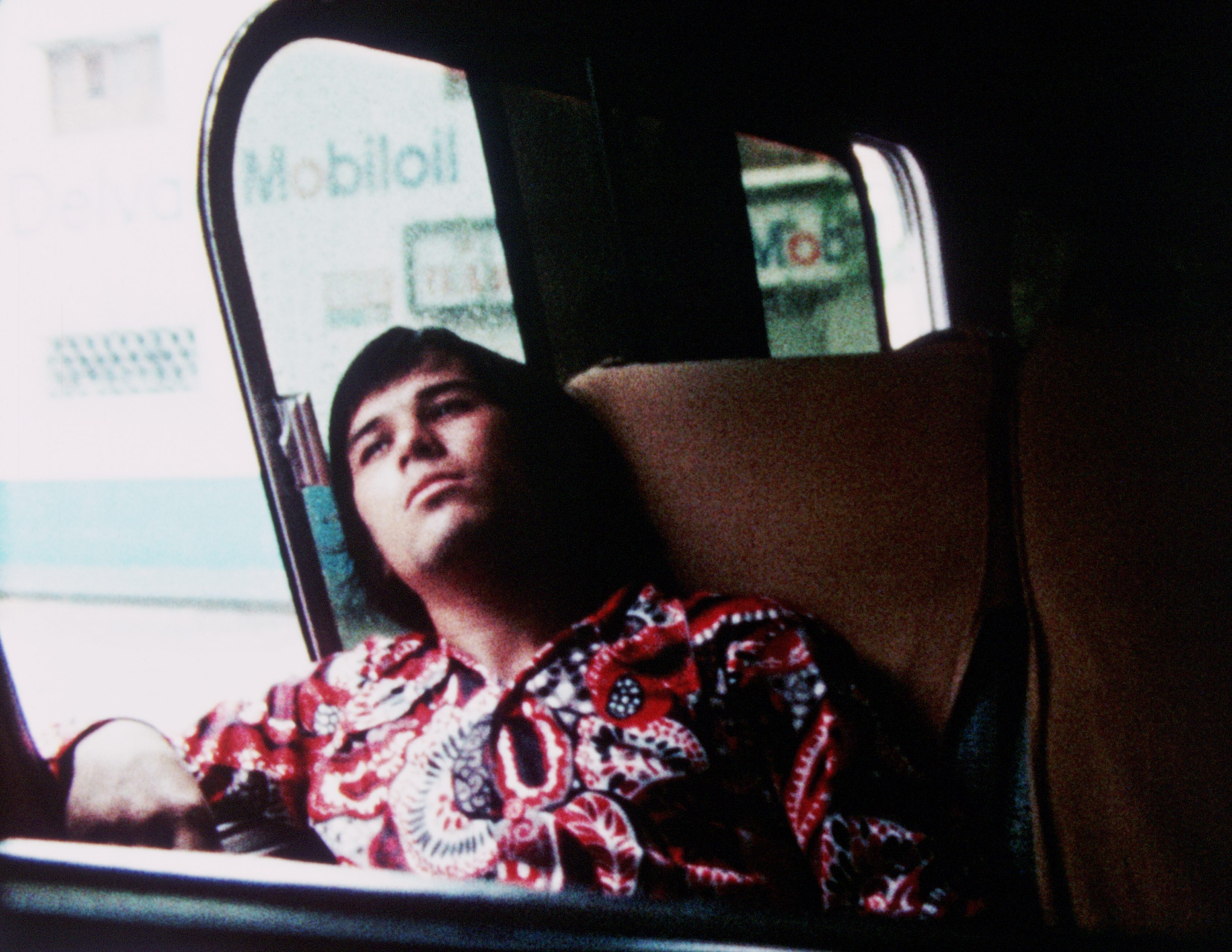 Man seated in vehicle with head leaning back against seat and window