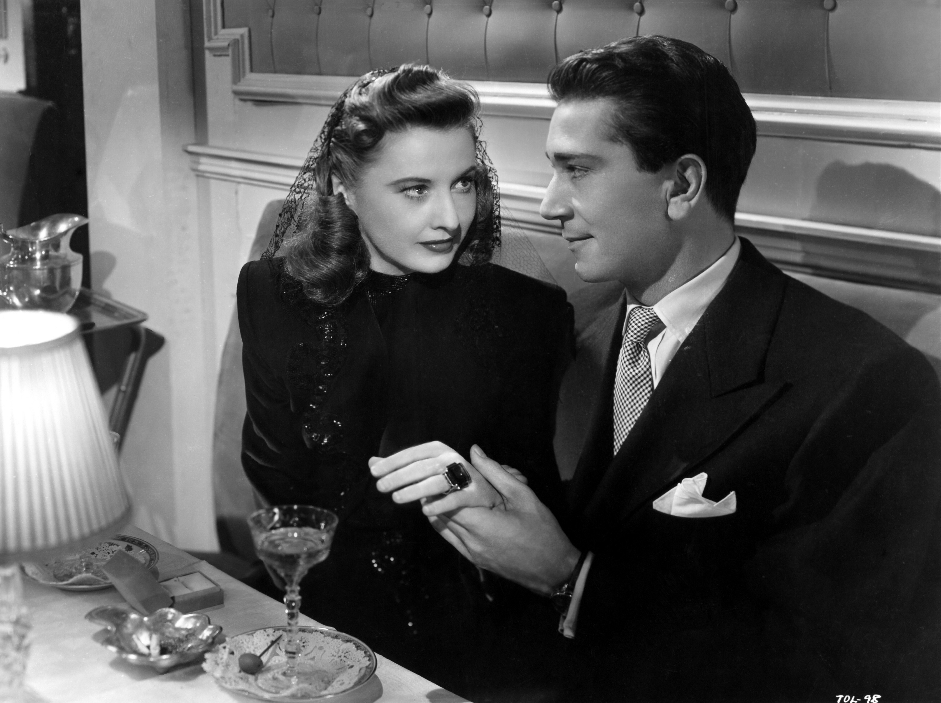 Man holding woman's hand while they're seated at a restaurant table