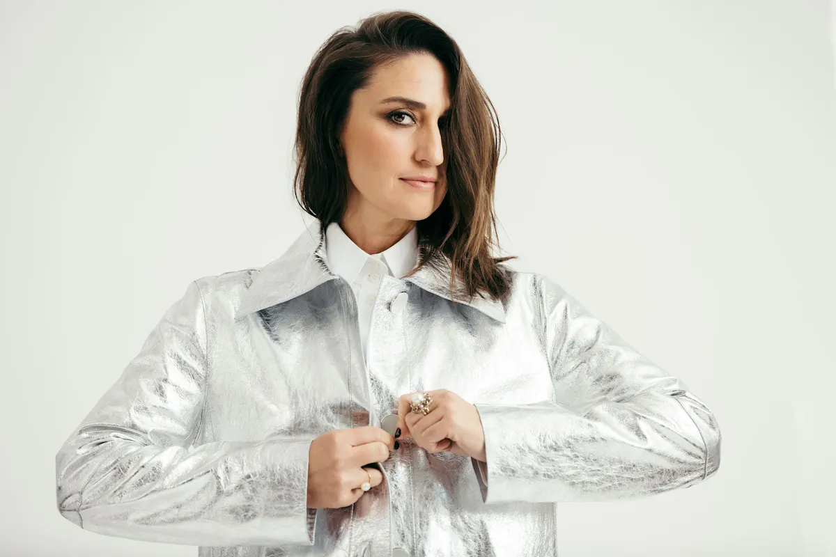 Portrait of Sarah Barielles. She is wearing a silver jacket. 