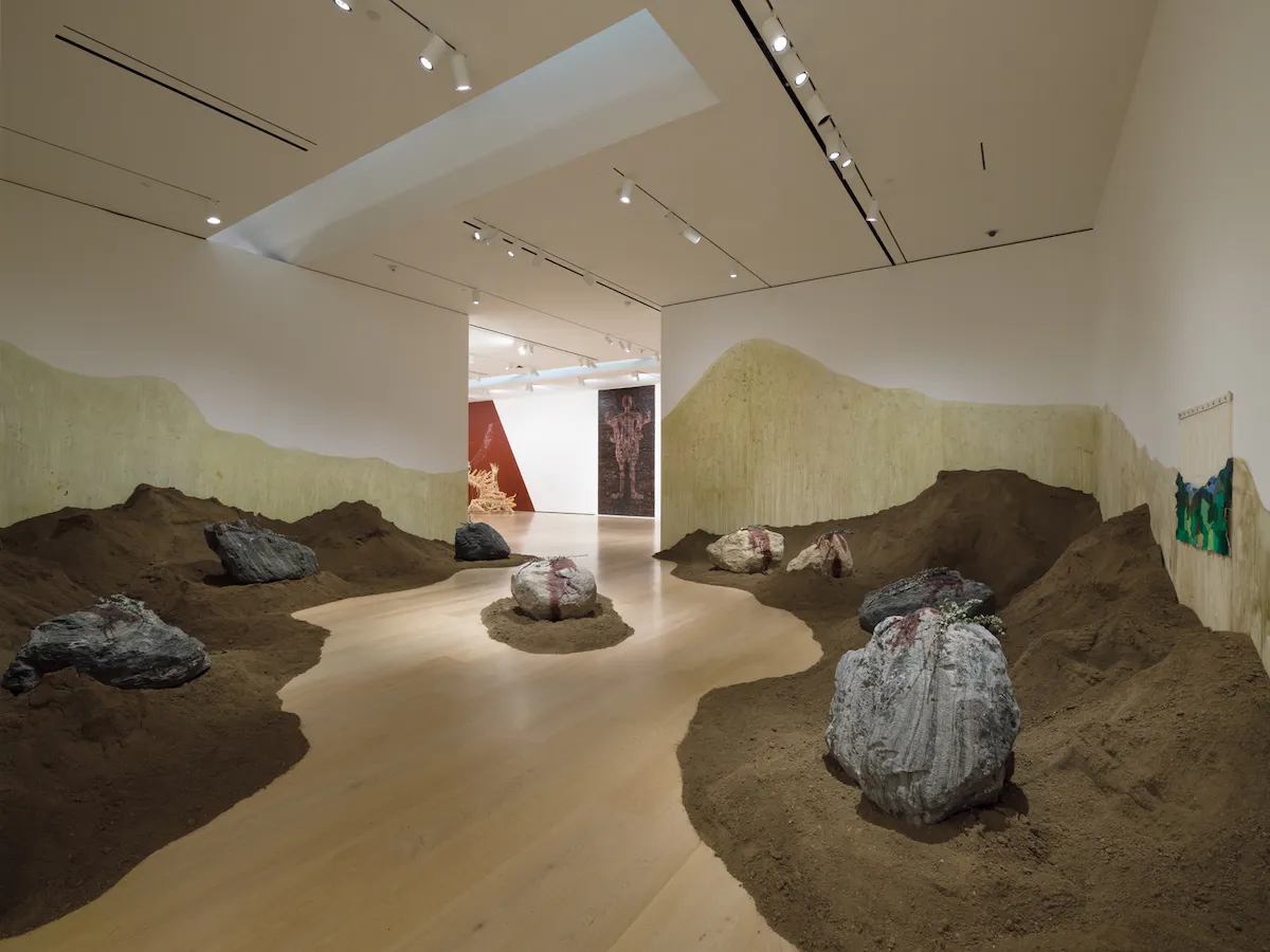 A sculpture made of piles of soil, large stones and eucalyptus branches in the Hammer Museum