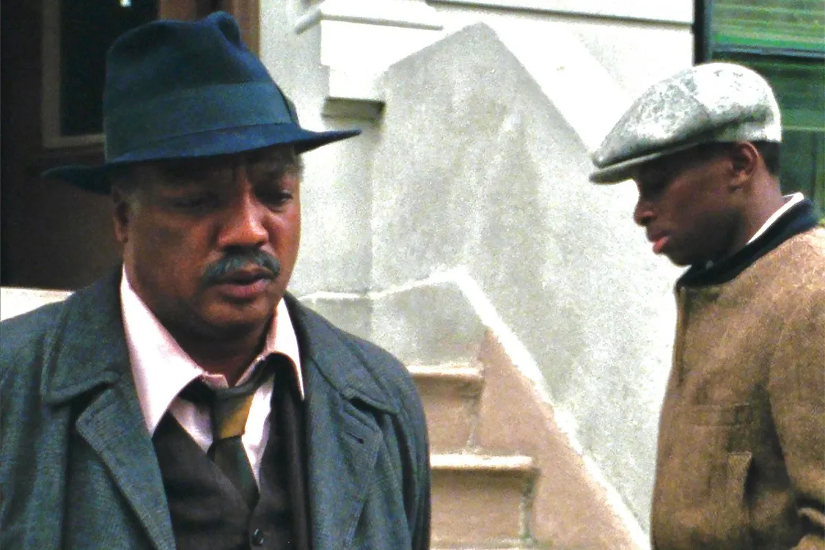 2 men. one is looking away and the other is turned towards the camera, but looking down